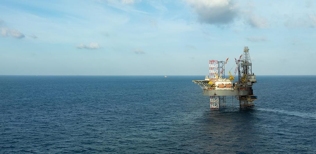 Aerial view of offshore oil rig in calm ocean waters.